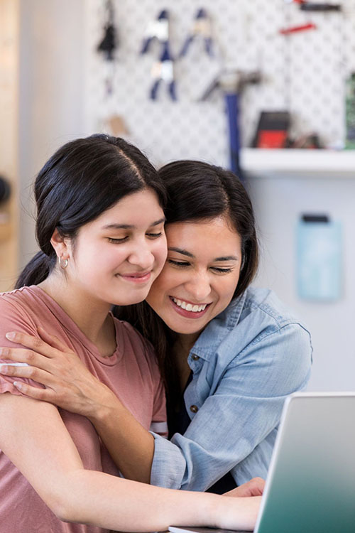 mom and daughter hugging in front of computer